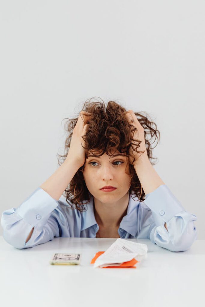 pexels-photo-7680365 Woman in Blue Long Sleeve Shirt Holding Her Head